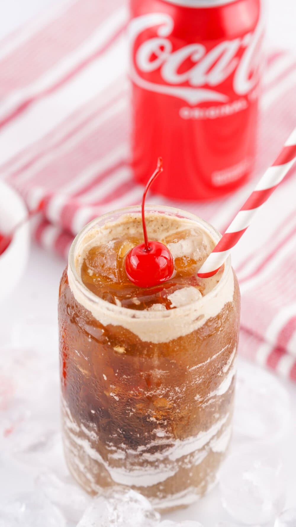 Glass of Fluffy Coke with the can of Coke in the background.
