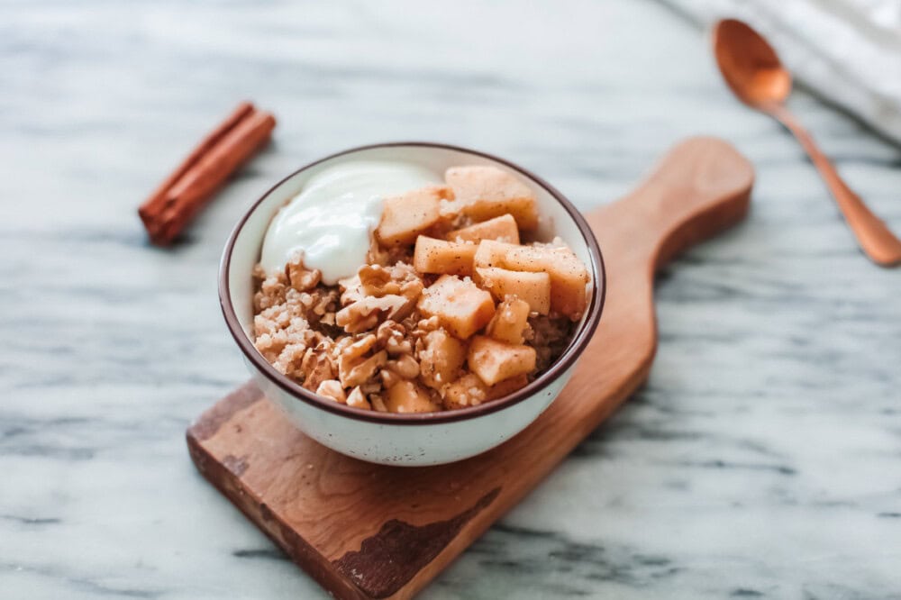 Bowl of quinoa topped with apples and yogurt.