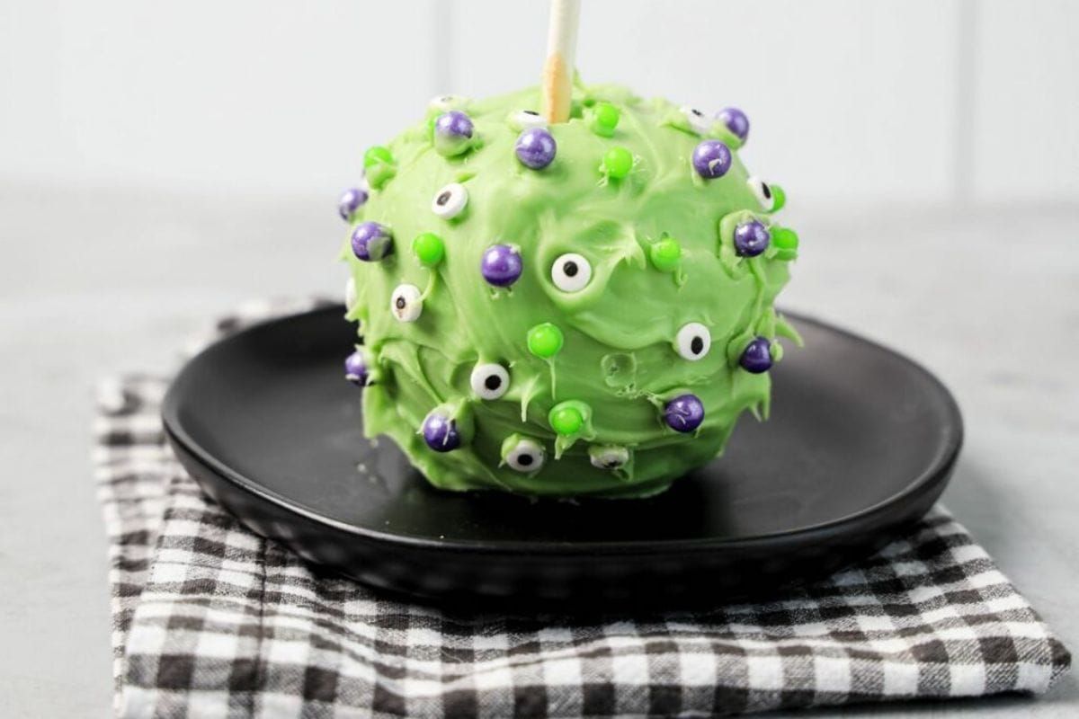 Green candy apple covered in candy eyes.