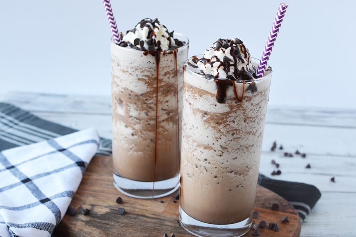 Two mocha frappuccinos in a glass with straws.