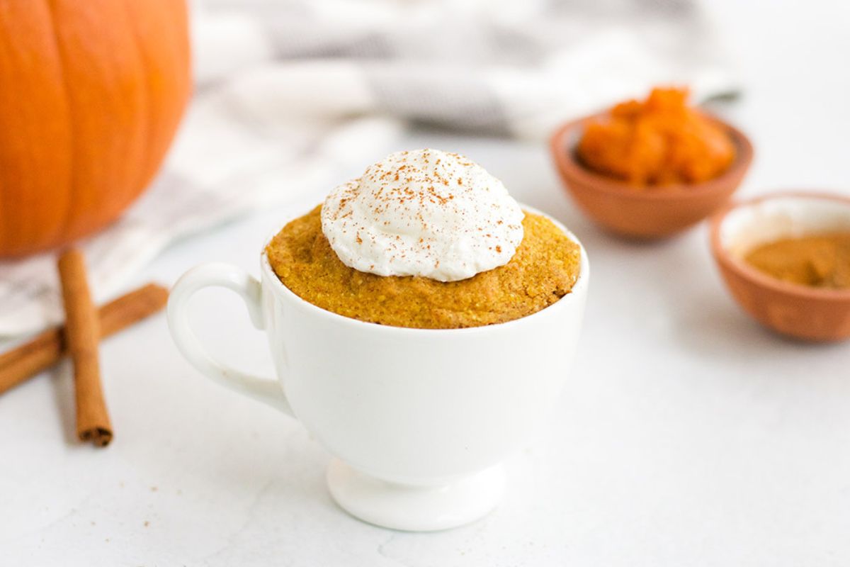 Pumpkin cake with whipped cream on top in a mug.