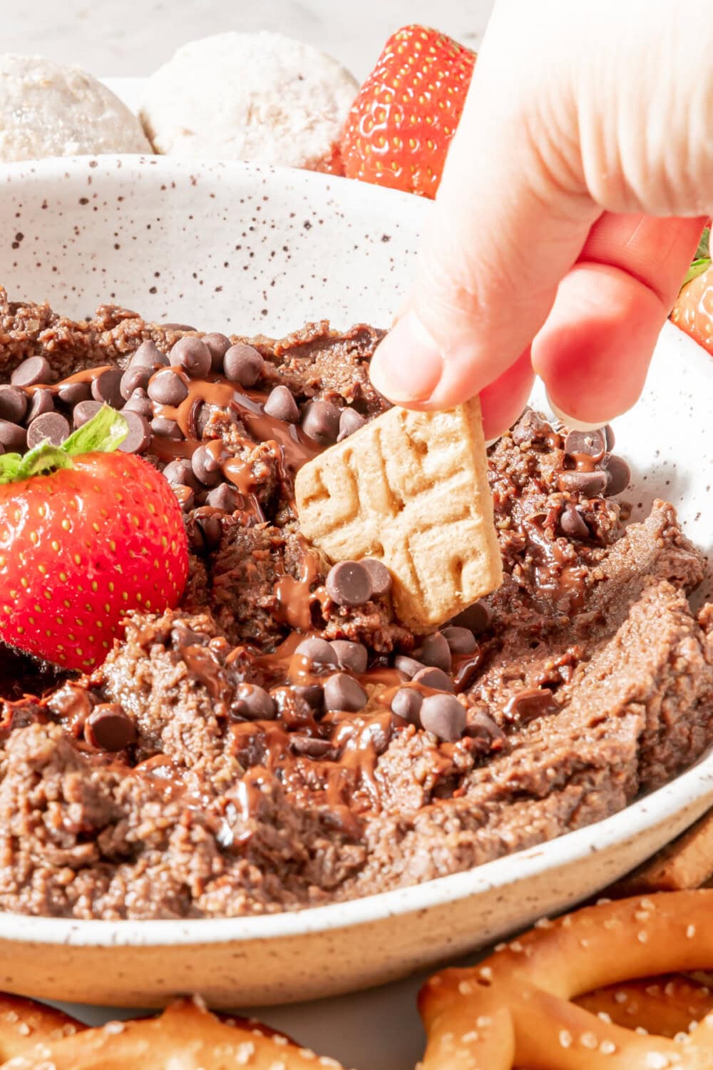 Dipping a cookie into dark chocolate chip hummus.