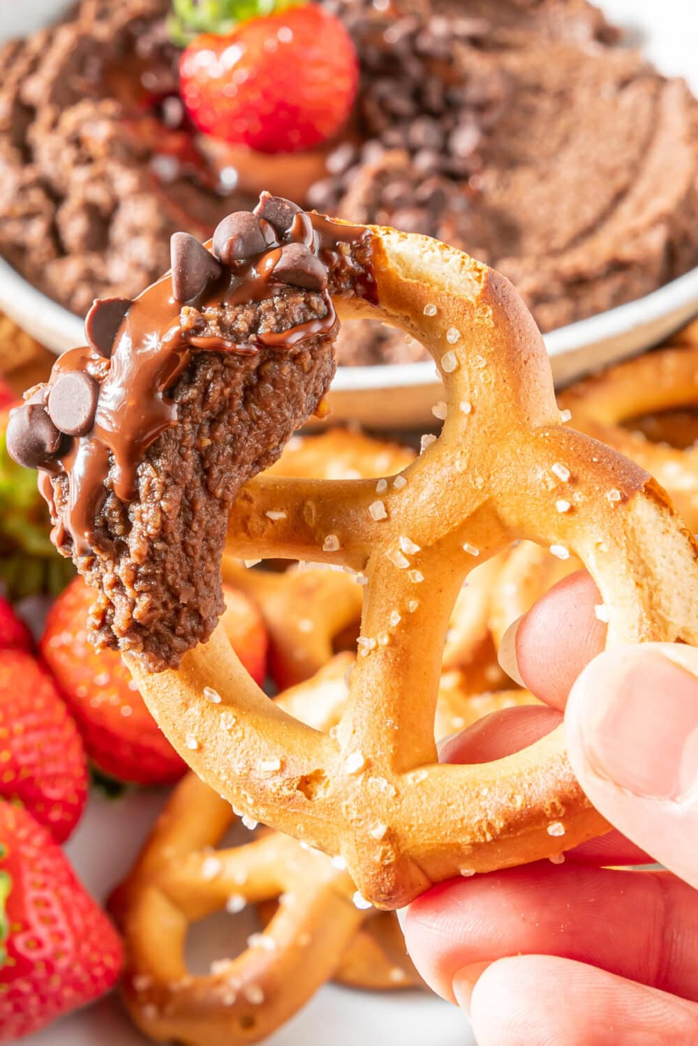 Dipping a pretzel into chocolate hummus.
