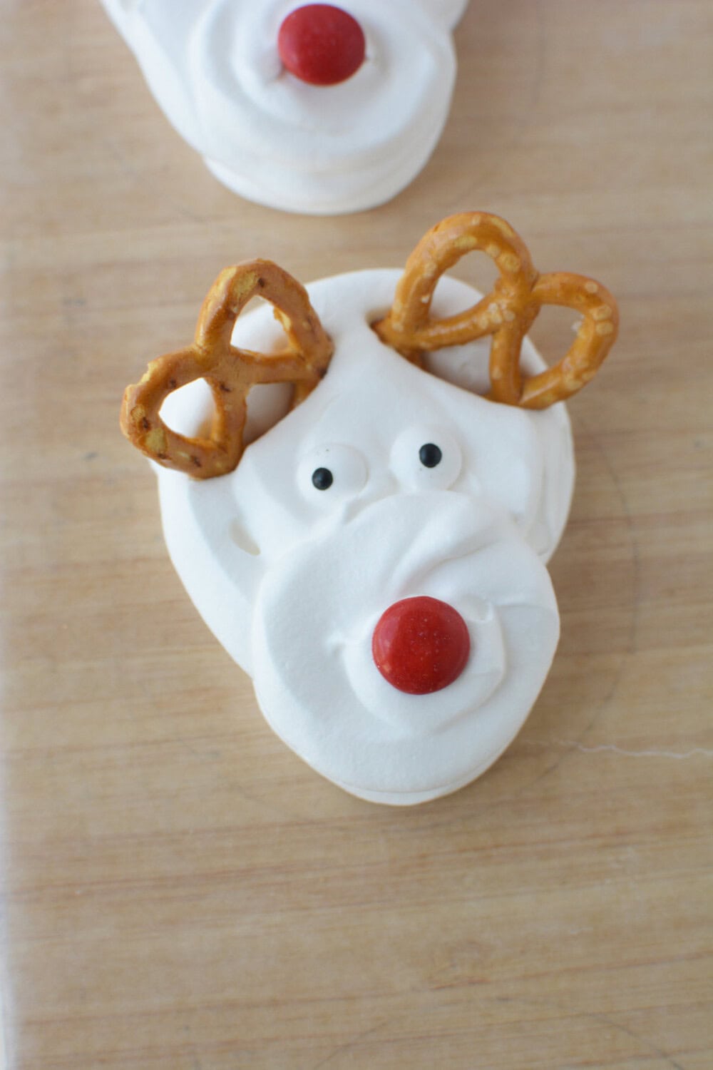Whipped cream with candy eyes, red M&M, and pretzel antlers