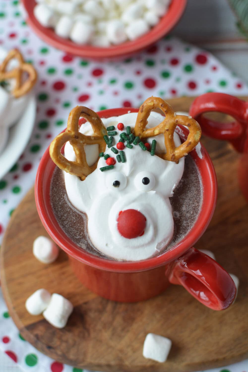Red mug of hot chocolate topped with a whipped cream reindeer