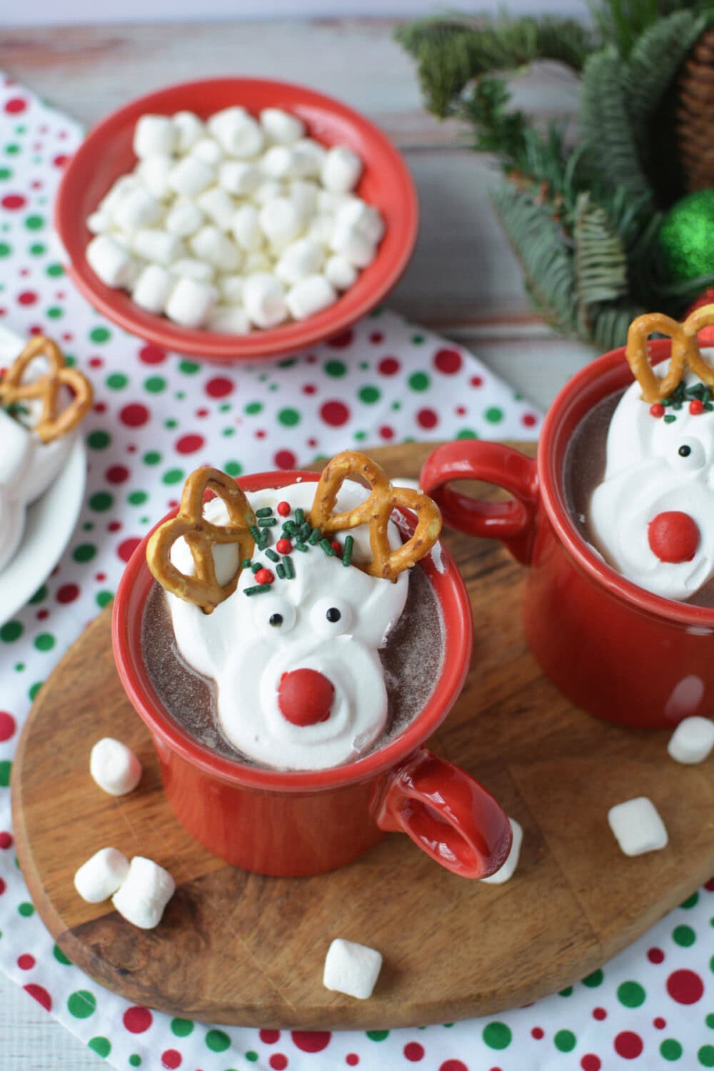 Hot chocolate mugs topped with whipped cream reindeer and marshmallows