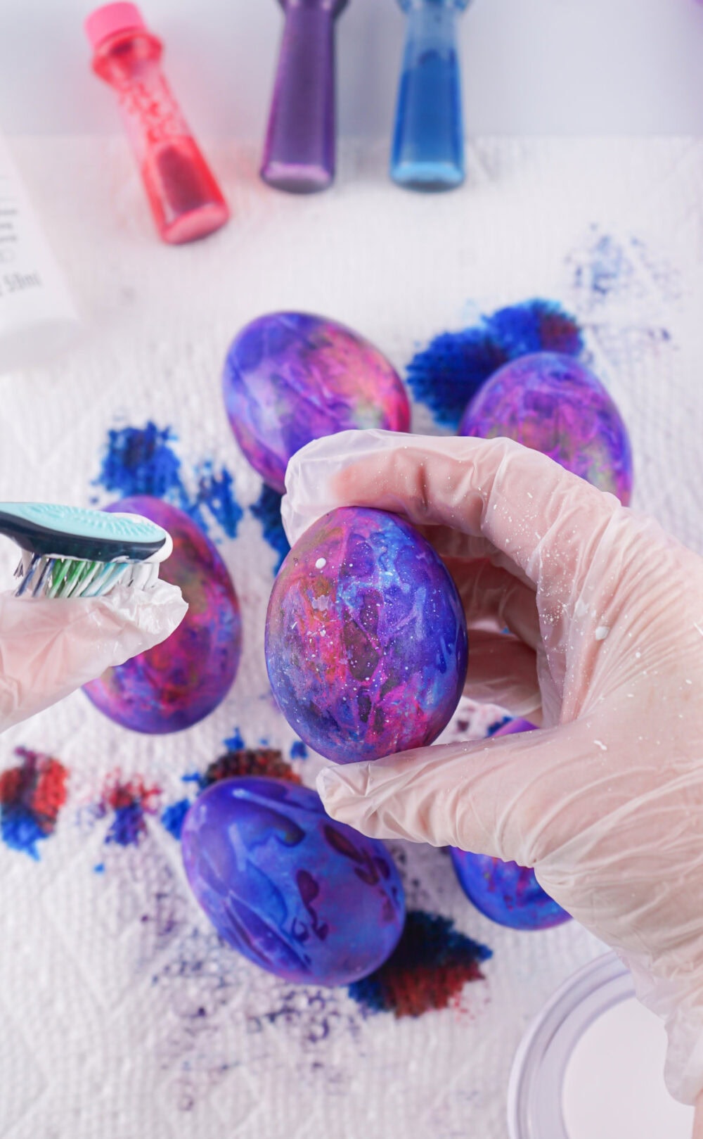 Flicking paint onto a dyed egg.