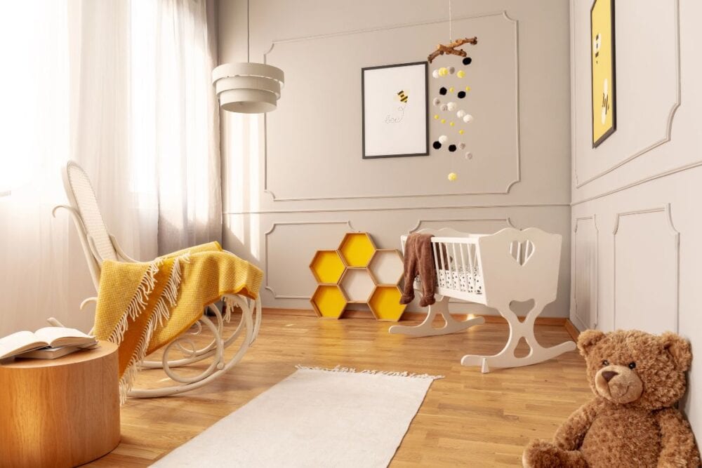 Bee-themed nursery with rocking chair, crib, and teddy bear. 