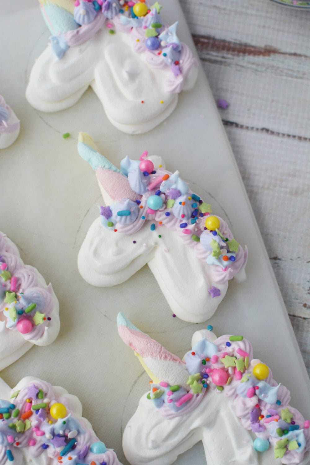 Decorating whipped cream unicorns with sprinkles